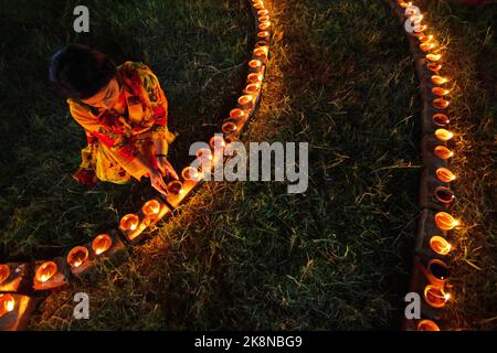 Narayanganj, Dhaka, Bangladesch. 24. Oktober 2022. Hindu-Anhänger beleuchten ''Diyas'' (irdene Lampen) auf einem Rangoli, einem Rahmen aus dekorierten Mustern, als Teil der Diwali-Feierlichkeiten in einem Tempelgelände in Narayanganj, Bangladesch. Viele leichte Öllampen oder Kerzen symbolisieren den Sieg des Lichts über die Dunkelheit, und im Rahmen der Feierlichkeiten werden Feuerwerke aufgesetzt. Das Festival findet jedes Jahr nach dem hinduistischen Mondkalender statt. Kredit: ZUMA Press, Inc./Alamy Live Nachrichten Stockfoto