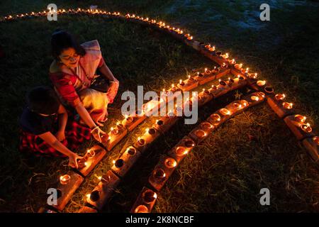 Narayanganj, Dhaka, Bangladesch. 24. Oktober 2022. Hindu-Anhänger beleuchten ''Diyas'' (irdene Lampen) auf einem Rangoli, einem Rahmen aus dekorierten Mustern, als Teil der Diwali-Feierlichkeiten in einem Tempelgelände in Narayanganj, Bangladesch. Viele leichte Öllampen oder Kerzen symbolisieren den Sieg des Lichts über die Dunkelheit, und im Rahmen der Feierlichkeiten werden Feuerwerke aufgesetzt. Das Festival findet jedes Jahr nach dem hinduistischen Mondkalender statt. Kredit: ZUMA Press, Inc./Alamy Live Nachrichten Stockfoto