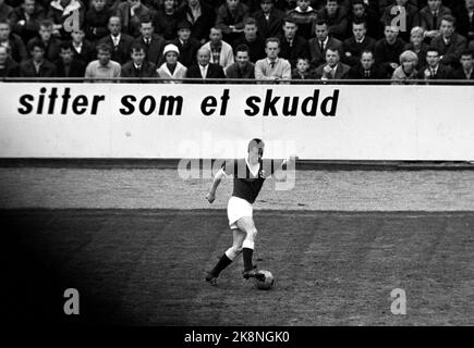 Bergen 19640701 Harald Berg, der 22-jährige Fußballspieler aus Bodø, ist der erste Vertreter einer nordnorwegischen Mannschaft, die in der A-Nationalmannschaft spielt. Er debütiert hier in Kampen Norwegen / Schweiz im Brann Stadium, und das Plakat im Hintergrund (das zugegebenermaßen der Hansa-Brauerei gehört) versichert, dass er wie ein Schuss sitzt. Harald 'Dotte' Berg in Aktion. Foto: Storløkken / Aktuell / NTB Stockfoto