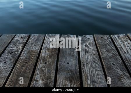 Holzbretter und Wasser, Mauerwerk auf dem See aus der Nähe. Stockfoto