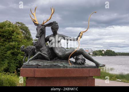 Schweden, Stockholm - 16. Juli 2022: Die ruhende Diana Bronzestatue auf rotem Marmorsockel entlang der Nobelgatan sitzt mit einem Reh und einem Bogen. Hupe Stockfoto