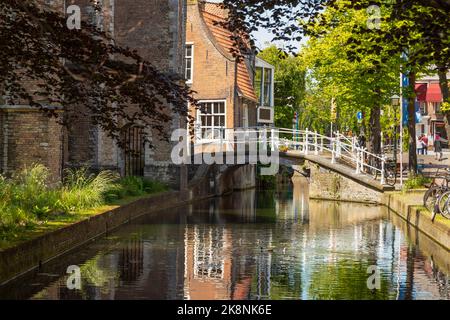 Blick auf die weiße Brücke über den Kanal im Stadtzentrum der historischen Stadt Delft. Stockfoto