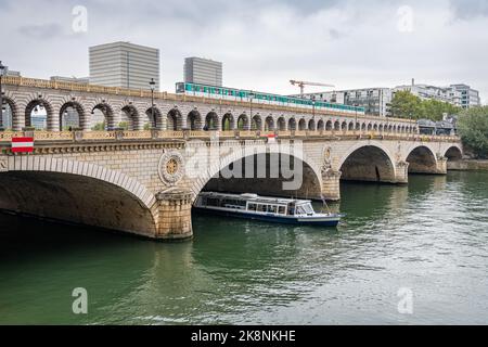 Pont de Bercy kombinierte die Straßen- und Eisenbahnbrücke über die seine mit einer Zugüberquerung und einem Boot, das unter der Brücke auftauche, Paris, Frankreich Stockfoto