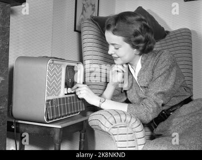 Oslo 19550209 'Mr. And Mrs. Lykke' Illustration Fotos zum Artikel über die glückliche Ehe, fotografiert von NTB im Februar 1955. Hier Frau Lykke in entspannter Pose in einem Sessel beim Radio. Reiseradio vom Typ Mascot, produziert von Østfold Radio. Foto: NTB / NTB das Modell heißt Ellinor Øygard, oft 'Bibba' genannt. Stockfoto