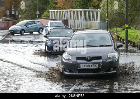 Yardley, Birmingham, 24. Oktober 2022. - Fahrer verhandeln sich am Montagnachmittag durch die Überschwemmungen auf der Yardley Green Road in der Yardley Gegend von Birmingham. Die Fahrer benutzten den Pfad auf der Seite, um entlang zu fahren und das tiefere Wasser zu vermeiden, aber einige Fahrer entschieden sich, durch die Mitte zu pflügen. PIC by Credit: Stop Press Media/Alamy Live News Stockfoto