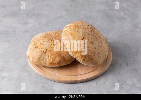 Pita-Brot auf Holzbrett auf neutralem Hintergrund. Nationale Küche. Traditionelles Gericht Stockfoto