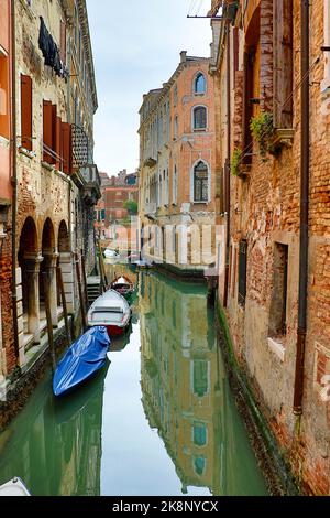 Eine vertikale Aufnahme eines Kanals in Venedig mit Gondeln, die auf dem Wasser schweben Stockfoto