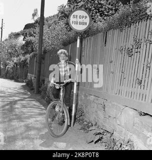 Kragerø 195406 - Sommerbilder aus Kragerø. Junge Frau mit Fahrrad neben Verkehrsschildern. „Vorsicht vor Kindern“. Foto: Current / NTB Stockfoto