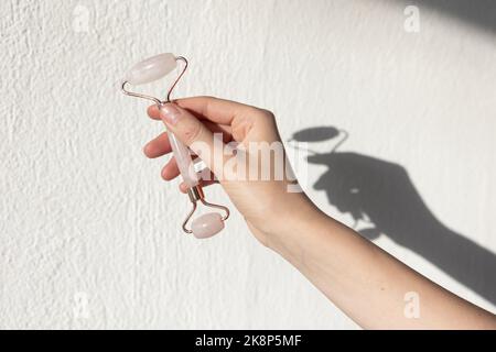 Gesichtswalze aus Steinjade und Massagegerät aus Gua Sha Rosenquarz. Gesichtspflege und Anti-Age-Produkte. Stockfoto