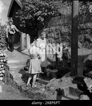 Drøbak 19470902 die Dürre und der Wassermangel im Sommer 1947 waren auch in Drøbak spürbar. Das Wasser war in Drøbak geschlossen, und jeder wurde dazu beordernet, Wasser in Eimern zu holen. Hier treffen sich die Frauen am Brunnen/Wasserpfosten, um die Eimer zu füllen. Im Hintergrund ein Postbote bei der Arbeit. FOTO: LYNAU / NTB / NTB Stockfoto