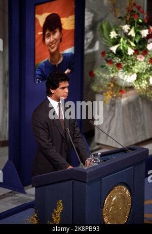 Oslo 19911210. Friedensnobelpreis 1991 an Aung San Suu Kyi, Oppositionspolitikerin in Burma. Aung San Suu Kyi befindet sich seit 1989 in Hausarrest, nachdem sie die Opposition gegen einen überlegenen Wahlsieg angeführt hatte, der vom Militär nie respektiert wurde. Die Auszeichnung wurde von der Familie des Friedenspreisträgers, Ehemann Michael Aris und den Söhnen Kim und Alexander Aris, entgegengenommen. Das Bild: Alexander Aris sprach im Namen seiner Mutter, Aung San Suu Kyi. Im Hintergrund ein Bild des Friedenspreisträgers. Foto: Bjørn Sigurdsøn/NTB Stockfoto