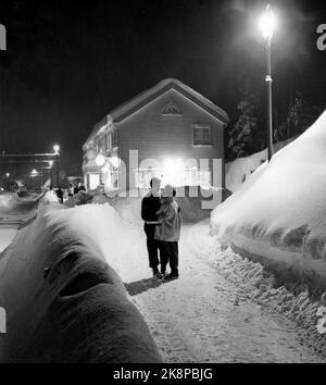 Kragerø 19540320. Südnorwegen steht kurz vor dem Erwürgen durch Schnee. Im Februar kippte der Schnee 23 Tage lang Tag und Nacht. Straßen waren blockiert, Züge schneiten hinein, Autos verschwanden unter den Schneemassen, an vielen Stellen fast nur der Schornstein, der über den Häusern hing. Auf dem Bild sehen wir ein Paar, das auf einem romantischen Abendspaziergang in der Menge des Schnees ist. Foto: Aage Storløkken / Aktuell / NTB Stockfoto