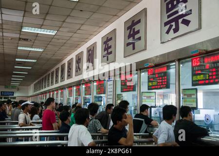 Pendler und Reisende stehen an einer Reihe von Kassenfenstern Schlange, um ihre Tickets für die Züge und die Zugfahrt zu kaufen. Stadt Xi'an, China (125) Stockfoto