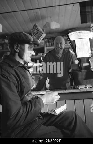 Rukkedalen in Hallingdal 1963 vom alten Landhändler in Rukkedalen in Hallingdal. Krambu. Länderhandel. Besitzer Arne S. Eidal hinter dem Tresen. Kunde vor der Theke. Der Kunde sitzt und rollt Rauch. Foto: Sverre A Børretzen / Aktuell / NTB Stockfoto