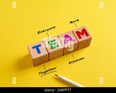 Synergiekonzept Business und Teamwork. Das Wort Team auf Holzwürfeln und Akronym mit Handschriftdefinition (gemeinsam erreicht jeder mehr). Stockfoto