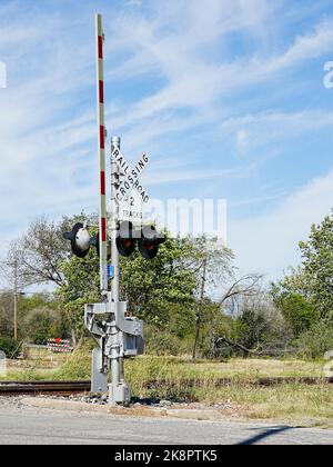 Warnsignal und Tor für Bahnstraßenübergänge. Blinklichter und Absenken des Torarms warnen Fahrer vor Annäherung an den Zug. Stockfoto