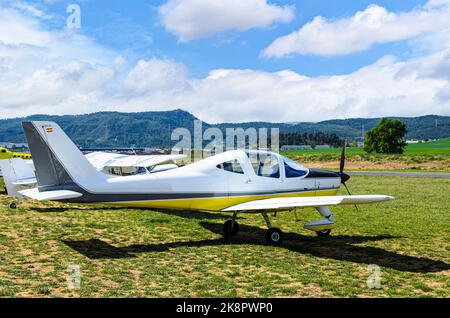 Ultraleichtes einmotorisches Flugzeug, das auf dem Flugplatz mit blauem Himmel und Feldhintergrund abheben soll Stockfoto
