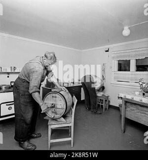 Flatdal in Telemark, August 1959. Fjellgården Ekre liegt 600 Meter über dem Meeresspiegel und in einem derart unwegsamen Gelände, dass "niemand denken würde, dass jemand es könnte BU". Die Familie betreibt natürliche Haushalte, darunter 3-4 Kühe, die gemolken werden müssen. Hier der Bauer selbst, Bjørn Ekre, als Kernbutter. / Kirche der Butter. Im Hintergrund wäscht einer der Farmjungen das Gesicht in einer Wasch-Schüssel. Foto: Aage Storløkken / Aktuell / NTB Stockfoto
