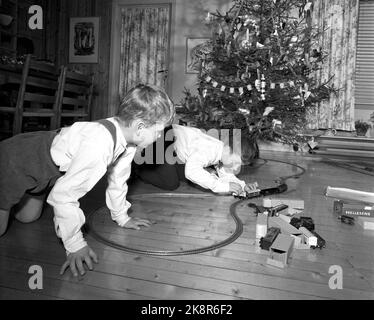 Oslo 195712. Heiligabend in der Familie Rørslett. Die Jungs spielen mit den Weihnachtsgeschenken, einem Zug und machen eine Zugstrecke auf dem Boden vor dem Weihnachtsbaum. Foto Sverre A. Børretzen / Aktuell / NTB Stockfoto