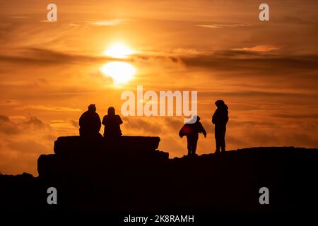 Portland, Dorset, Großbritannien. 24. Oktober 2022. Besucher trotzen den wehenden Meereswinden, um den Sonnenuntergang in Portland Bill in Dorset an einem unSaison warmen Tag in Südengland zu sehen. Kredit: Peter Lopeman/Alamy Live Nachrichten Stockfoto