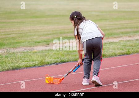 Russland. Vyborg 06.06.2021 Mädchen spielen mit einem Hockeyschläger im Stadion ist kein Laufband. Hochwertige Fotos Stockfoto