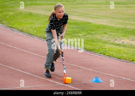 Russland. Vyborg 06.06.2021 Mädchen spielen mit einem Hockeyschläger im Stadion ist kein Laufband. Hochwertige Fotos Stockfoto