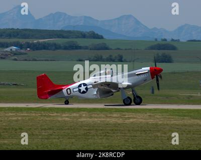 Die nordamerikanische P-51 Mustang WWII Kämpfer, Bomber Flugzeuge Rollen auf Springbank Flughafen auf grünen Hügeln Hintergrund Stockfoto