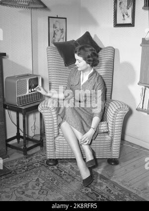 Oslo 19550209 'Mr. And Mrs. Lykke' Illustration Fotos zum Artikel über die glückliche Ehe, fotografiert von NTB im Februar 1955. Hier Frau Lykke in entspannter Pose in einem Sessel beim Radio. Reiseradio vom Typ Mascot, produziert von Østfold Radio. Foto: NTB / NTB das Modell heißt Ellinor Øygard, oft 'Bibba' genannt. Stockfoto