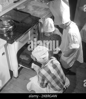 Oslo Weihnachten 1958. Kinder backen Lebkuchen. Eines Tages während der Weihnachtszeit interessierten sich die Jungen der Mutter plötzlich für häusliche Aktivitäten und begannen, die Küche zu benutzen, die den Mädchen vorbehalten war. Ein Bäcker ist kein Bäcker ohne Schürze und Backhut Papa's Shirt und eine weiße Papiertüte hat den Dienst getan. Das Ergebnis war so erfolgreich, dass kein Lebkuchenmann in die Box kam. Sie gingen im Magen der Bäcker. Der große Moment ist nun gekommen. Die Herdtür könnte geöffnet werden und die vorgekochten Kuchen werden entfernt. Foto: Aage Storløkken NTB / NTB Stockfoto