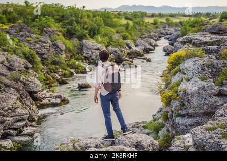 Mann Tourist auf dem Hintergrund der malerischen Niagarafälle auf dem Fluss Cievna. Montenegro, in der Nähe von Podgorica. Reisen Sie durch Montenegro Konzept Stockfoto