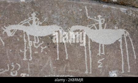 Zwei Reiter auf Pferden, die auf Felsen schnitzen: Alte Seidenstraßenpetroglyphen über dem Dorf Langar im Wakhan-Korridor, Gorno-Badakshan, tadschikisches Pamir Stockfoto