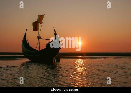 Blick auf die Landschaft bei Sonnenuntergang auf das traditionelle hölzerne Fischerboot, das als Mondboot bekannt ist, am Strand in der Nähe von Cox's Bazar im Süden von Bangladesch Stockfoto