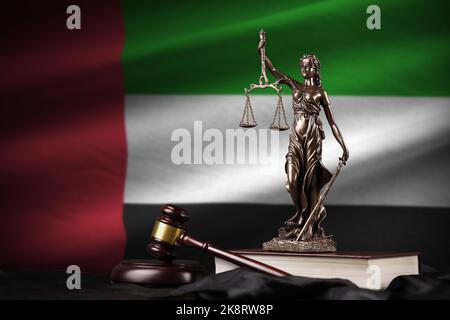 Flagge der Vereinigten Arabischen Emirate mit Statue der Justizdame, Verfassung und Richterhammer auf schwarzem Tuch. Konzept von Urteil und Strafe Stockfoto