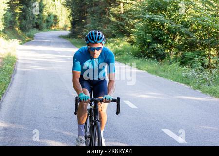 Kaukasischer Rennradfahrer, der auf einer offenen Radroute bergauf fährt Stockfoto