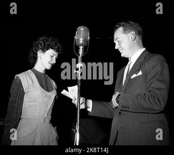 Oslo 1955 NRK Radio hat einen großen Erfolg mit dem Fragebogen "die Frage" von dem großen Glas Rolf Kirkvaag geführt. Das Konzept ist einfach und die Preise sind bescheiden, aber die Stimmung im Studio ist am Siedepunkt! Hier Kirkvaag in Aktion mit einem der Teilnehmer. „Geht es weiter?“ Kirkvaag fragt und Fans mit Tierne. Großes, altmodisches Mikrofon in der Mitte des Bildes. Foto: Storløkken / Aktuell / NTB Stockfoto