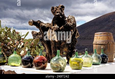 Alter Baumstumpf, Flaschen Wein und Weinfass vor einer Bodega - Lanzarote, Spanien Stockfoto