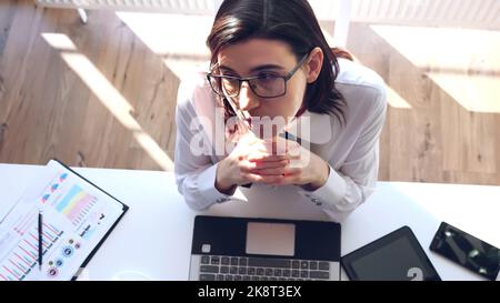 Kurze Pause, Ruhe im Arbeitsprozess in Modern Office. Überblick über junge Geschäftsfrau, Analytikerin, Buchhalterin, die mit Dokumenten arbeitet, New Business Project, sitzend am Laptop-Monitor,. Hochwertige Fotos Stockfoto