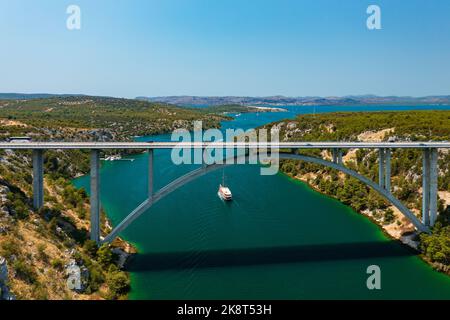 Luftaufnahme über die Krka-Brücke und den Fluss in der Nähe von Skradin. Boot, das durch den Fluss fährt. Stockfoto