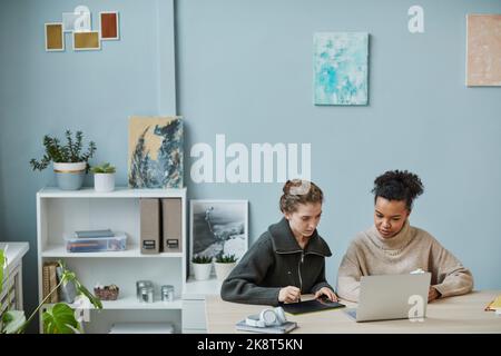 Zwei junge Designer, die im Büro mit Online-Projekten im Team arbeiten, nutzen Grafiktabletts und Laptops Stockfoto