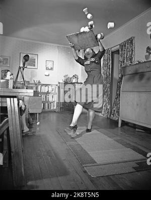 Oslo 19540109 Sie sind in Gefahr, wo Sie hingehen das Zuhause ist ein gefährlicheres Arbeitsumfeld, als viele Hausfrauen wissen. Hausunfälle, Illustration Foto. Ein loser Teppich ist kein Scherz. Frau rutscht auf den Teppich und verliert das Brett mit Kaffeetassen. Foto: Sverre A. Børretzen / Aktuell / NTB Stockfoto