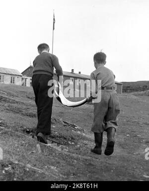 Nordkapp på Magerøya 195210. Europas nordligste internatskole ligger på Nordkapp i Repvåg ytterst i Porsangerfjorden. Åtte småsteder var skoleskøyta innom for å hente små passasjerer Fra 7 års alderen. Et par AV plasse hadde kai så skøyta kunne gå helt Inn, men som regel måtte den ligge utpå Og vente på robåten med ungen Og kofferten. Nordkapp herred--kommunen har skoleinternat for barna som bor på små avsidesliggende plasser innenfor herredsgrensene. Det er unger Fra anslagsvis 75 familier. Her kommer to AV elevene med stor fisk som de bærer mellom seg opp til internatet. Foto: Sv. A. Børr Stockfoto