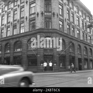 Oslo 19550922. Der Nachtclub Original Pilsen. Zu dieser Zeit war es an der Ecke von Dronningens Tor und Tollbugata. 5-stöckiges Gebäude in einfachem Historismus. Die beiden unteren Stockwerke sind in vertikale, geteilte Flächen in verputzten Ziegeln unterteilt. Zwei Kellner in weißen Jacken stehen an den Eingangstüren. Straßenbahnschienen und elektrische Aufhängungen für Straßenbahnen prägen ebenfalls das Bild. Ein Auto kommt vom linken Bildrand. Foto: NTB Archive / NTB Stockfoto