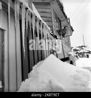 Kragerø 19540320. Südnorwegen steht kurz vor dem Erwürgen durch Schnee. Im Februar kippte der Schnee 23 Tage lang Tag und Nacht. Straßen waren blockiert, Züge schneiten hinein, Autos verschwanden unter den Schneemassen, an vielen Stellen fast nur der Schornstein, der über den Häusern hing. Der Schnee lag meterhoch in den Straßen und der Schnee Tag und Nacht. Auf der Insel versucht einer der Bezirke von Kragerø Karl Klausen aus dem zweiten Stock, im ersten Stock den Schnee vom Fenster zu holen. Eiszapfen. Foto: Aage Storløkken / Aktuell / NTB Stockfoto