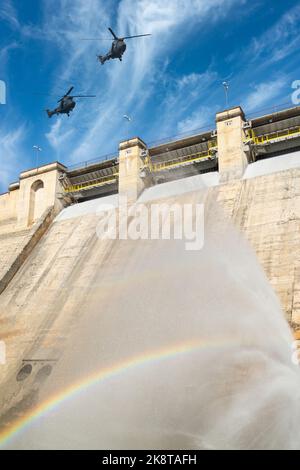 Militärhubschrauber fliegen über die Staumauer. Konzept/zusammengesetztes Bild. Ukraine, Russland, Krieg, Kraftwerk, Russisch, Energie, Kriegsverbrechen... Stockfoto
