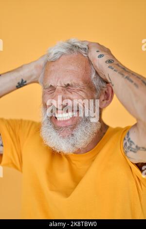 Glücklich lustig älter bärtig tätowiert Mann lachend isoliert auf gelb. Stockfoto