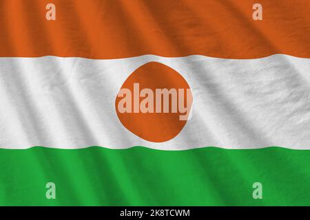 Niger-Flagge mit großen Falten, die aus nächster Nähe unter dem Studiolicht im Innenbereich winken. Die offiziellen Symbole und Farben in Stoff Banner Stockfoto
