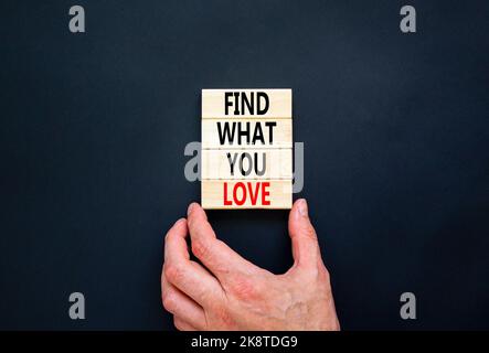 Finden Sie, was Sie lieben Symbol. Concept Words Finden Sie auf Holzblöcken, was Sie lieben. Schöne schwarze Tabelle schwarzen Hintergrund. Geschäftsmann Hand. Business, Psyc Stockfoto