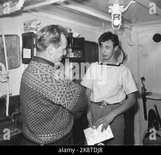 Grenze Jakobselv, Finmark Dezember 1962. Verteidigungsminister Gudmund Harlem soll an die Grenze zu Jakobselv mit Weihnachtsgeschenken für die Männer gehen, die über die Grenze zur Sowjetunion sprechen. Die Reise dauerte 5 Tage und wurde zu einer harten Reise mit Flugzeug, Auto, Boot und Pulk. Hier ist Byssgutt Andersen an Bord des Kontrollschiffs 'Gos III', der ebenfalls ein Weihnachtsgeschenk vom Verteidigungsminister (v.v.) erhielt. Andersen ist 16 Jahre alt und der jüngste an Bord. Foto: Ivar Aaserud Current / NTB Stockfoto
