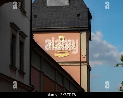 Gebäude der Bierbrauerei Radeberger mit einem großen goldenen Logo an der Fassade. Das Sonnenlicht beleuchtet das Schild an der Außenwand des Unternehmens. Stockfoto