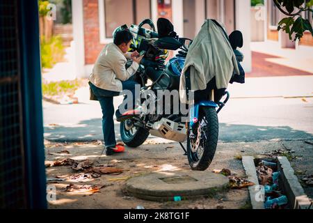 YAMAHA XT1200Z 'Super Tenere' Motorrad mit einem Kind, das ein Mobiltelefon in der Nähe benutzt. Stockfoto